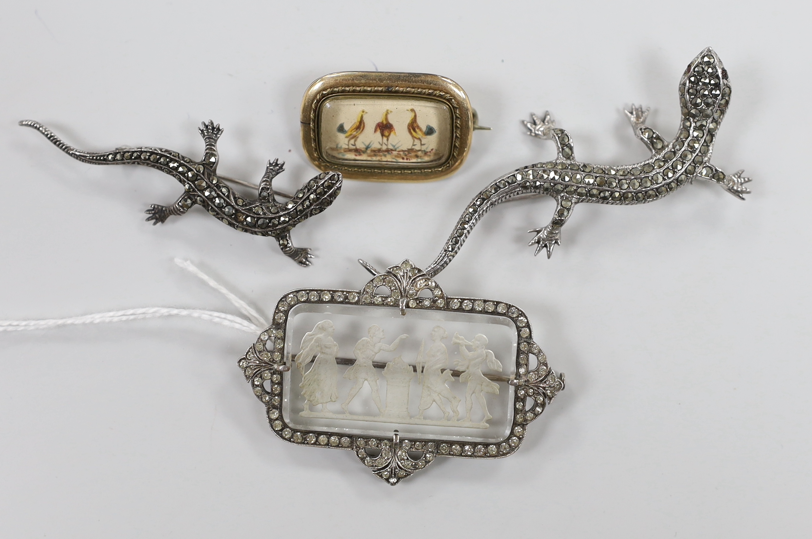 A 1920's French white metal and paste set etched glass brooch, 53mm, two marcasite lizard brooches and a Victorian yellow metal mounted brooch, decorated with three cockerel.
